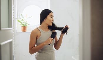 Woman brushing hair in bathroom