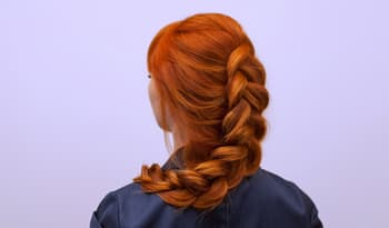 woman with red hair in a braid showing off thick and full hair