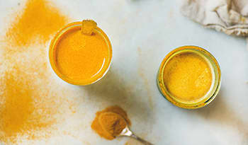 Glasses of golden turmeric milk on white table