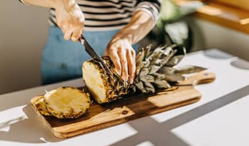 Woman in apron cutting pineapple