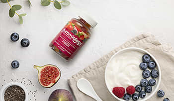 Fiber gummy supplements on white table with yogurt and fresh fruit