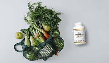 Green bag of fresh produce with multivitamins