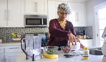 Mature woman making healthy smoothie at home