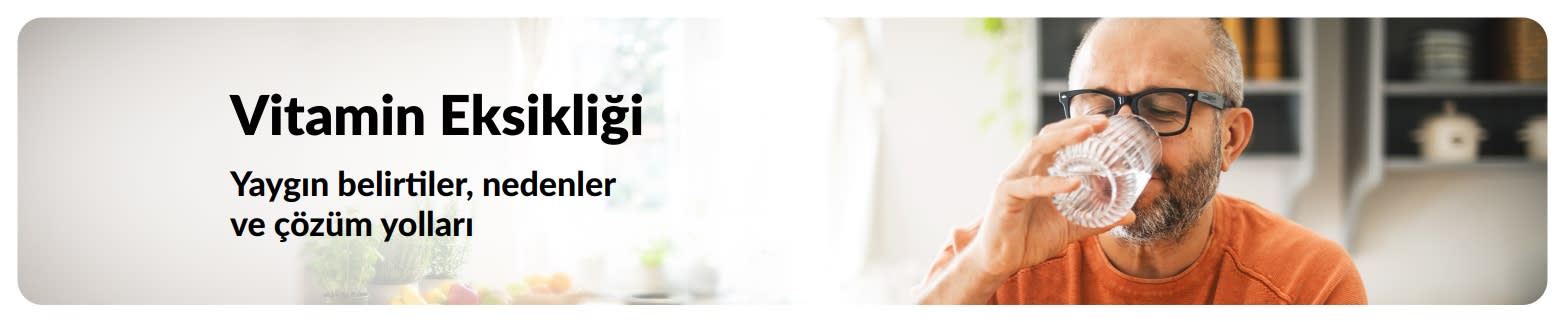 Evde su içen bir erkeğin yer aldığı, belirtiler ve nedenler üzerine metin içeren vitamin eksikliği blog banner’ı