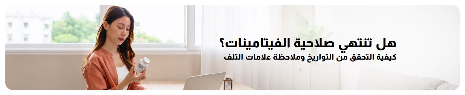 امرأة تفحص عبوة فيتامين في المنزل بجوار جهاز الكمبيوتر المحمول، مع نص: هل تنتهي صلاحية الفيتامينات؟ كيفية التحقق من التواريخ وملاحظة علامات التلف.