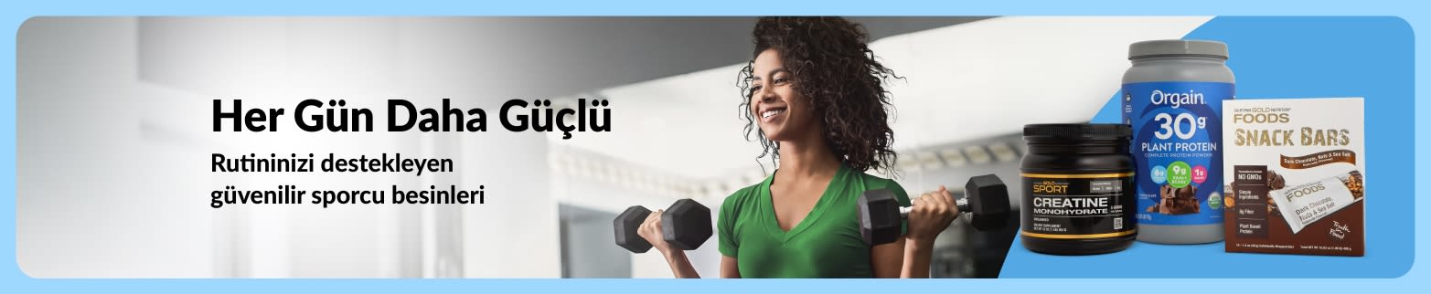Spor salonunda dambıl kaldıran bir kadın, yanında sporcu besinleri ürünleri ve “Her Gün Daha Güçlü Rutinleriniz için güvenilir sporcu besinleri.” mesajı