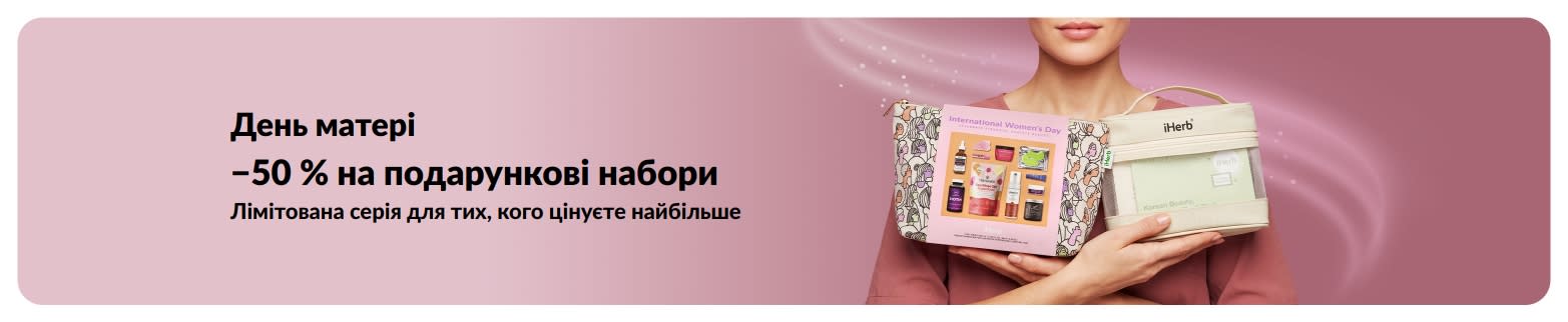 Банер до Дня матері зі знижкою 50% на подарункові набори із зображенням жінки, що тримає подарункові набори iHerb.