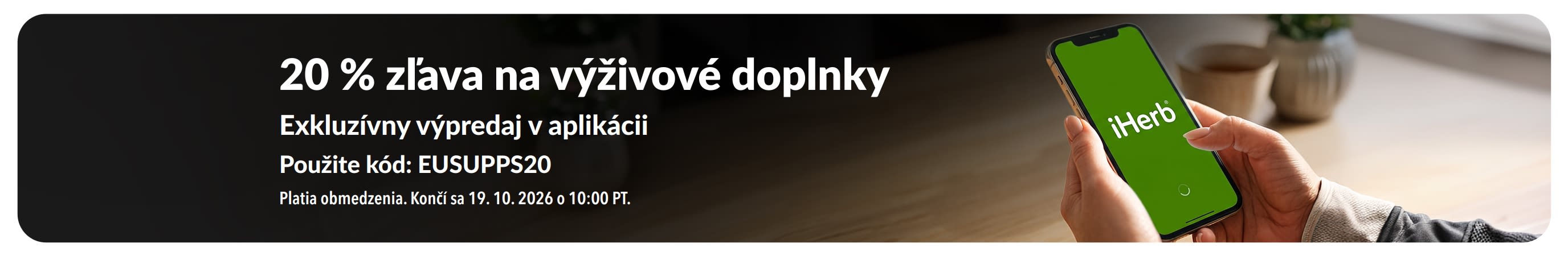 Ruky, ktoré držia v ruke mobil s aplikáciou iHerb, propagujúce 20 % zľavu na výživové doplnky s kódom EUSUPPS20.