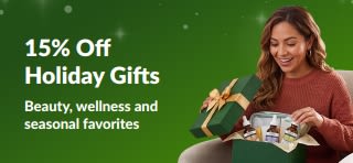 15% off holiday gifts promotional banner showing a woman opening a gift box filled with beauty and wellness skincare products.