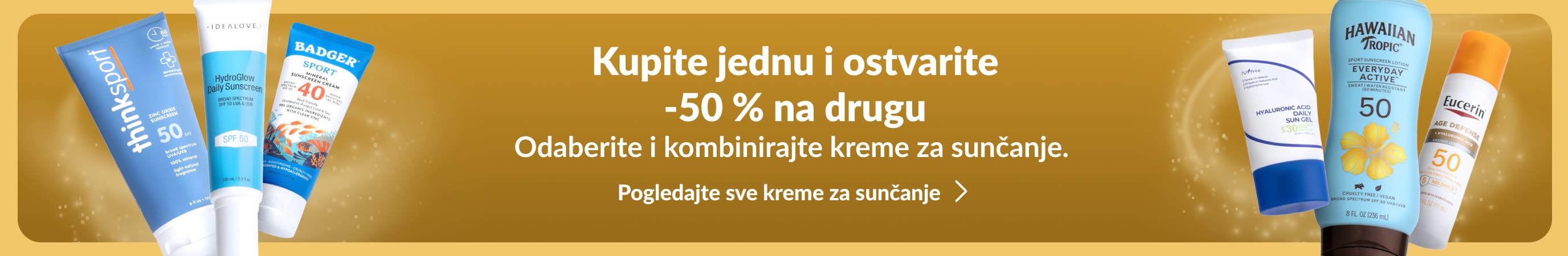 Dvije skupine različitih proizvoda za zaštitu od sunca nalaze se s obje strane zlatnog reklamnog natpisa. Promotivni tekst na reklamnom natpisu glasi: „Kupite jednu i ostvarite -50 % na drugu kremu za sunčanje.”