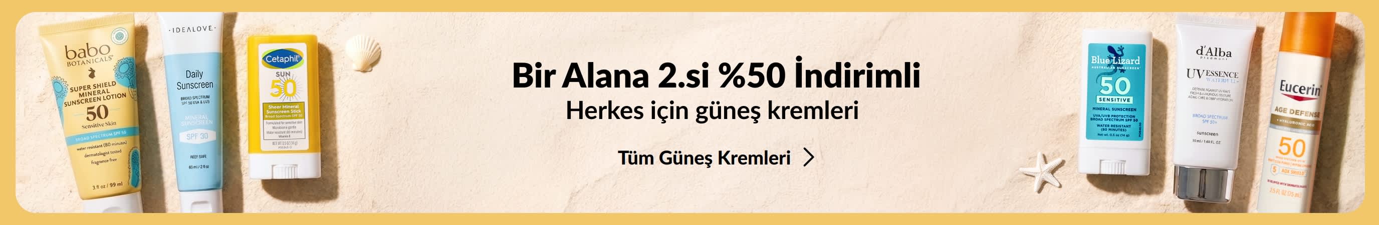Altın bir bannerın iki yanında farklı güneş kremi ürün grupları. Banner üzerindeki promosyon metni: “1 Alana 2.si %50 İndirimli güneş bakım ürünleri.”